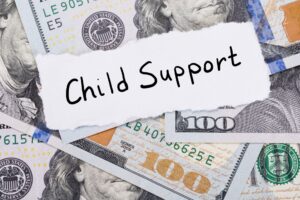 Child support written on a piece of paper on top of hundred dollar bills